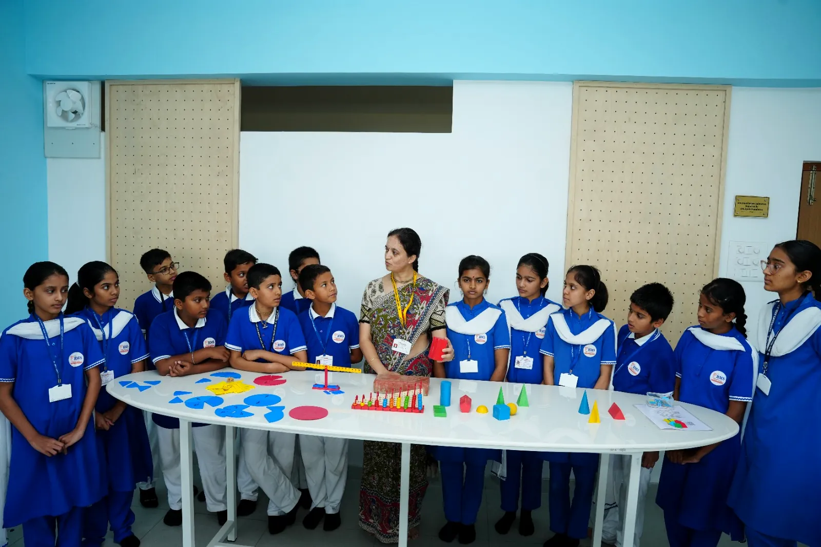 Students around the oval activity table with mathematics manipulatives