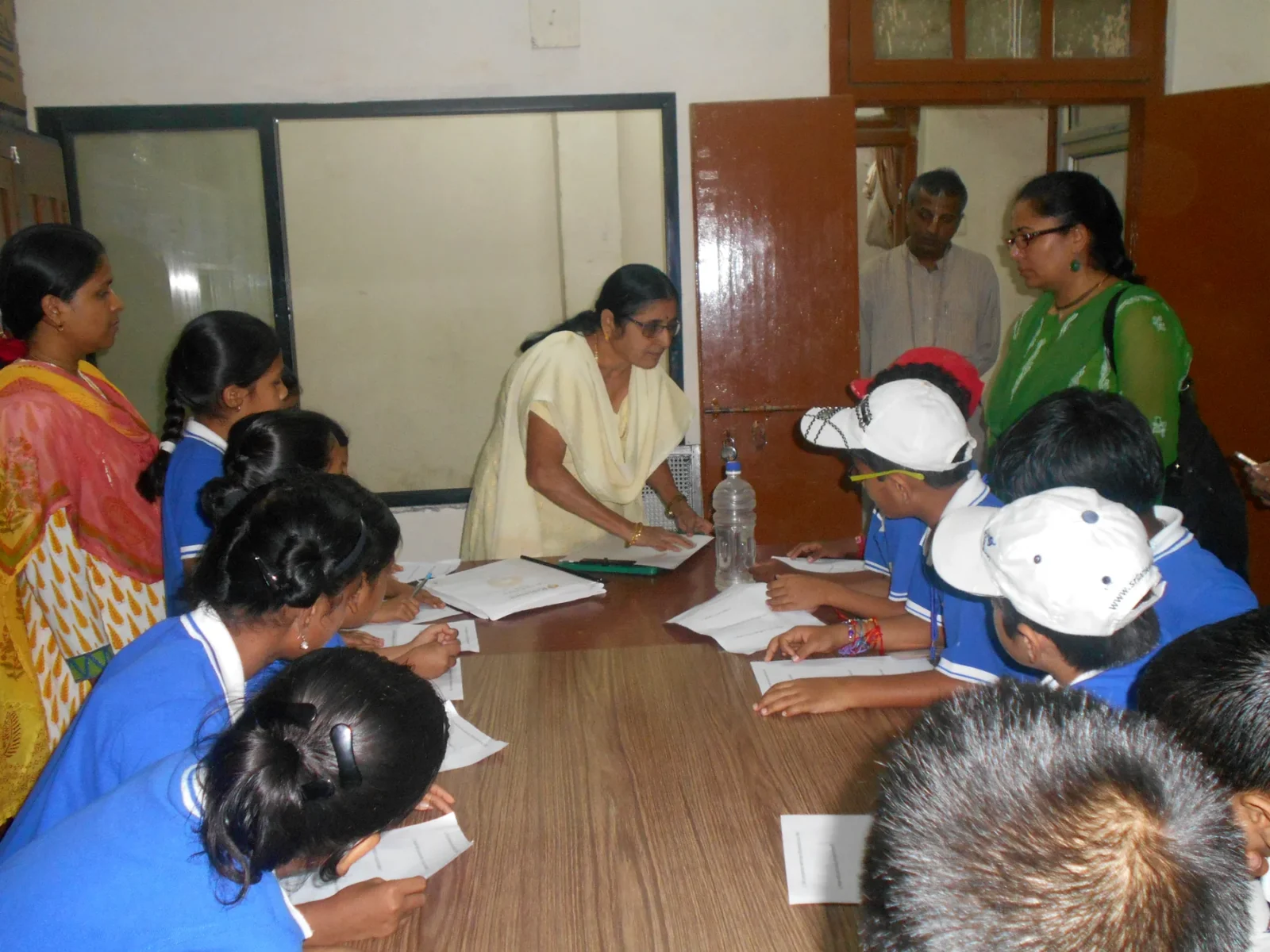 Students seated around the table with their teachers during an assessment