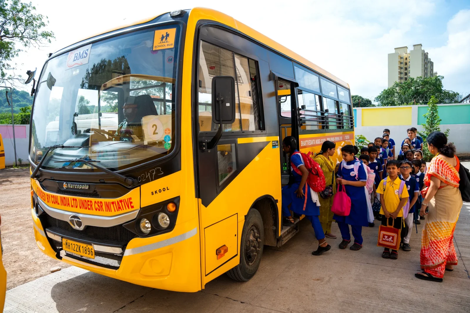 Students boarding the school bus at the end of the day, with staff supervising