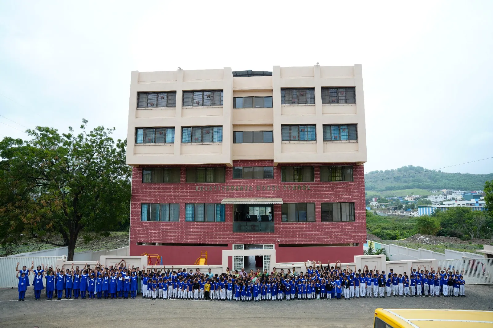Wide view of the school block on its own land, with the hills of Yewalewadi behind