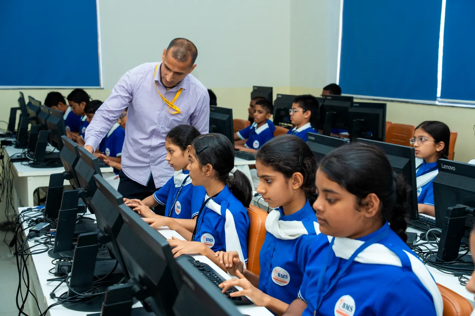 Students at work in the computer laboratory, with their teacher helping along the row of workstations
