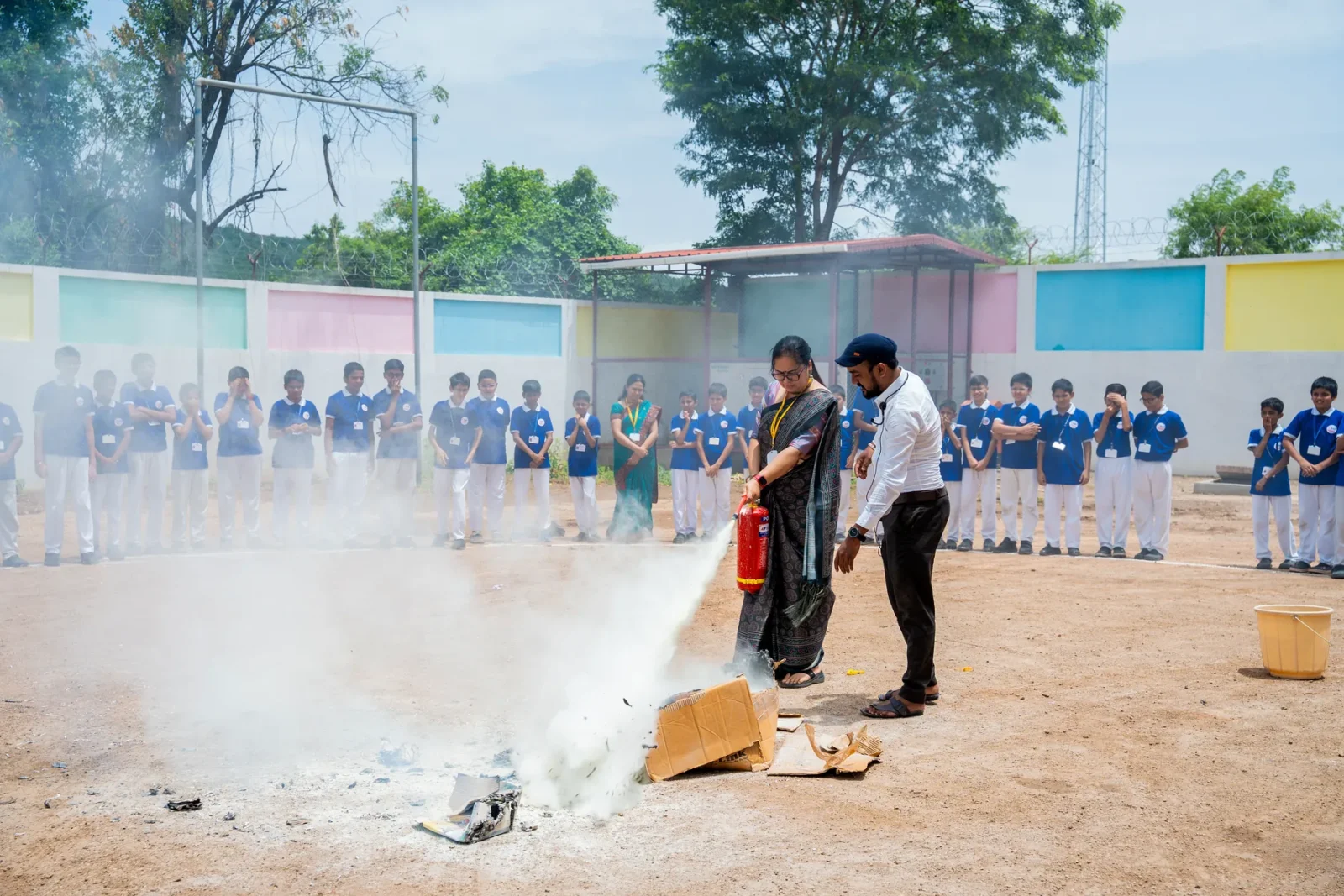 A fire extinguisher demonstration during a drill, watched by the whole school