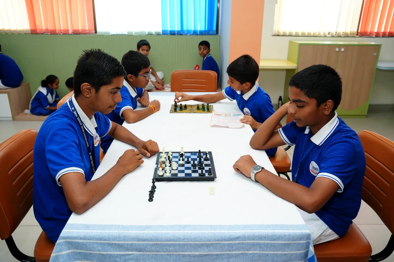 Students playing chess at the indoor games tables