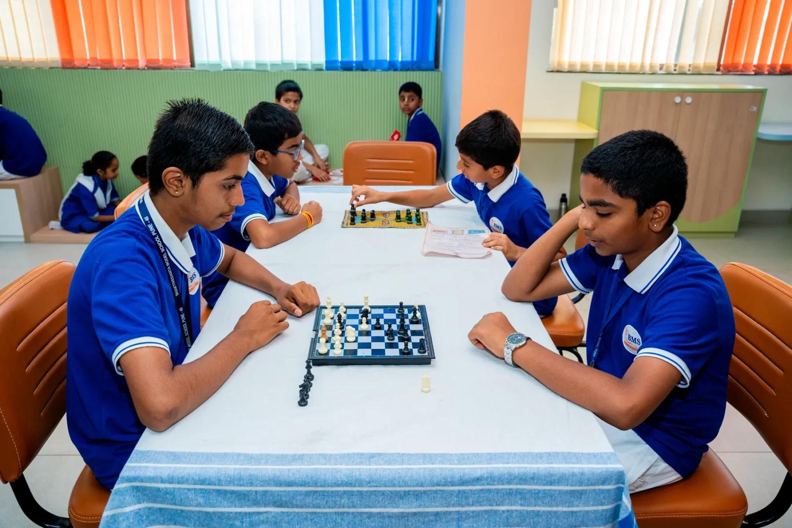Two students concentrating over a game of chess in the indoor games room