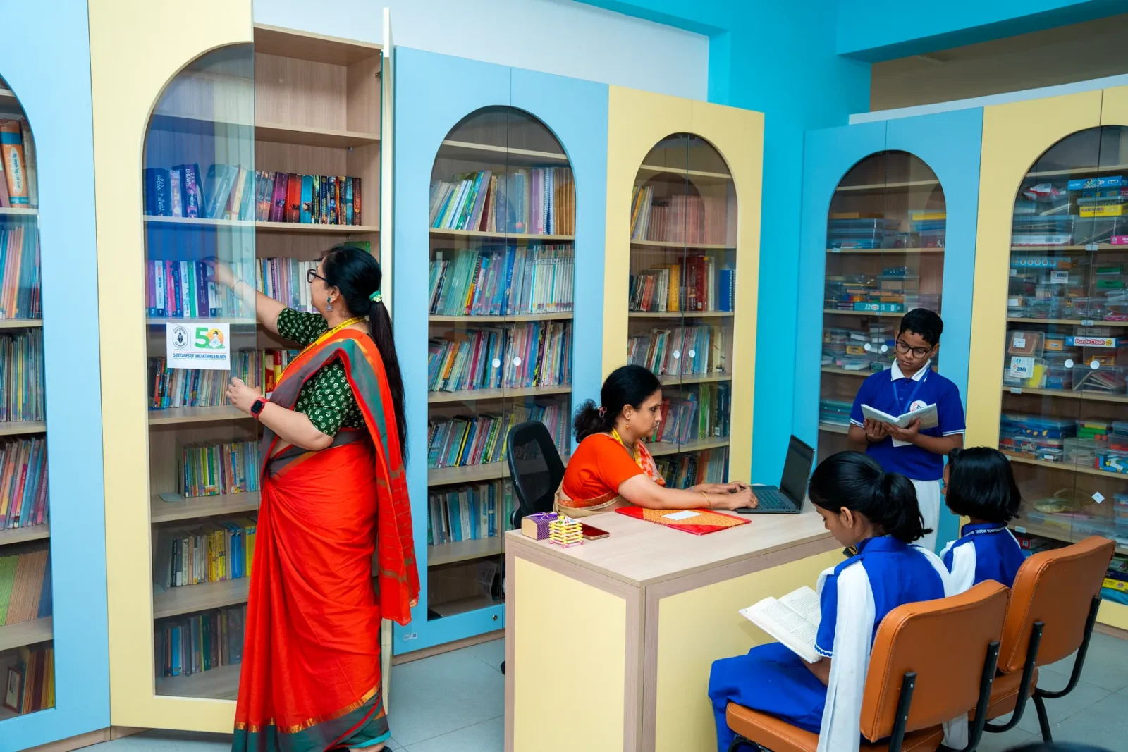A teacher reading with students in the library's reading corner