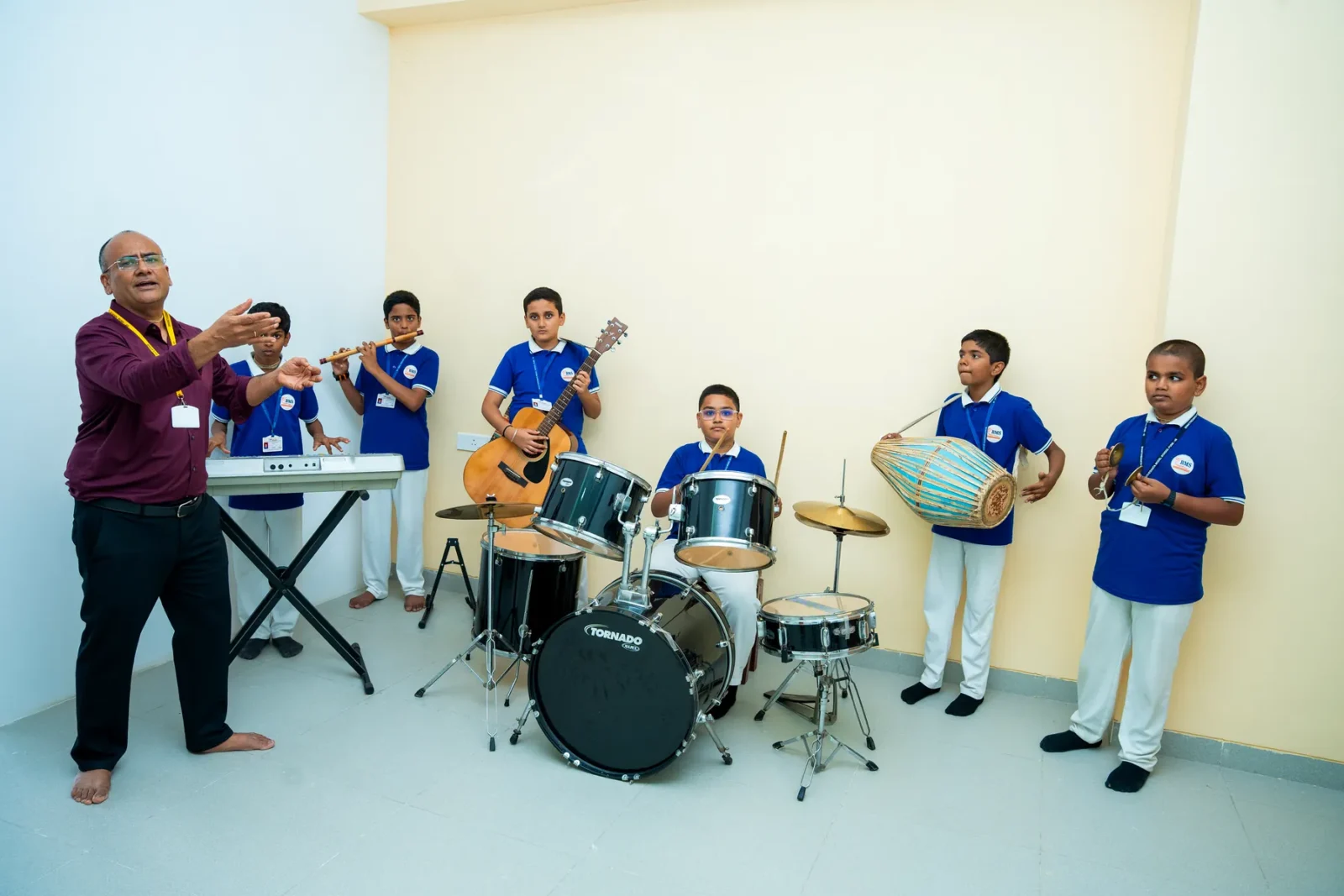 Students playing drums, tabla, keyboard and guitar with their music teacher