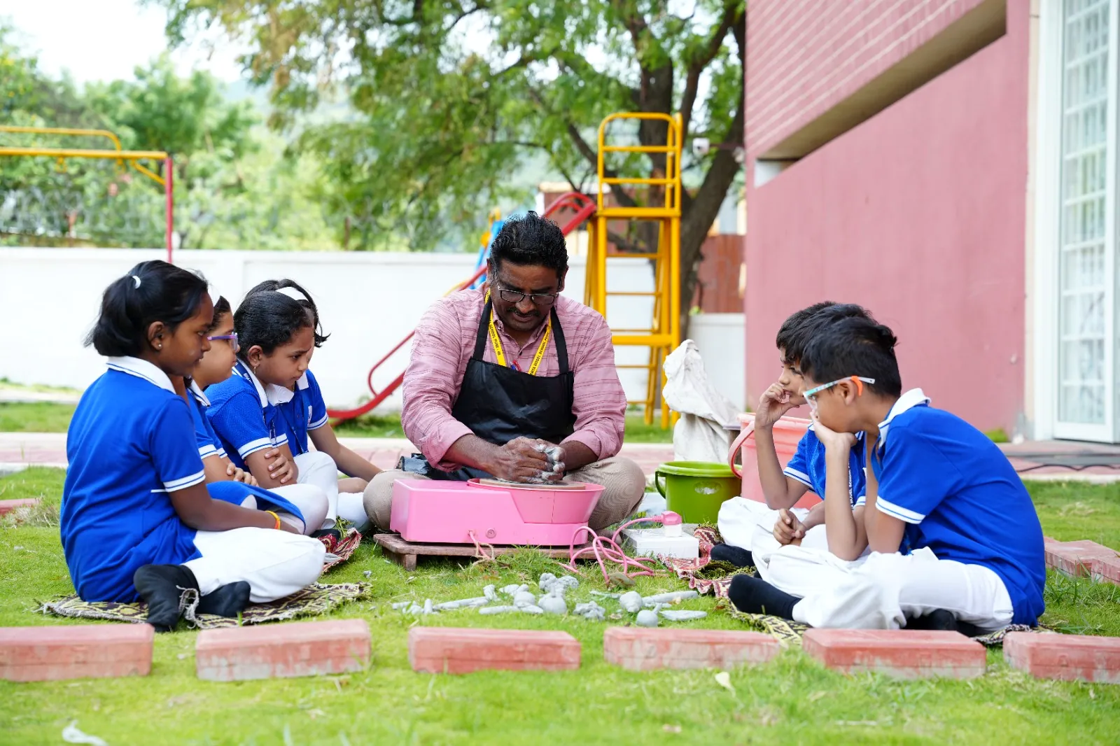 A primary class seated on the lawn for an outdoor lesson