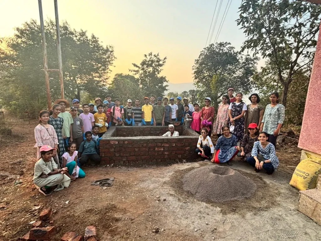 Children and teachers with the brick structure they built during a community service visit