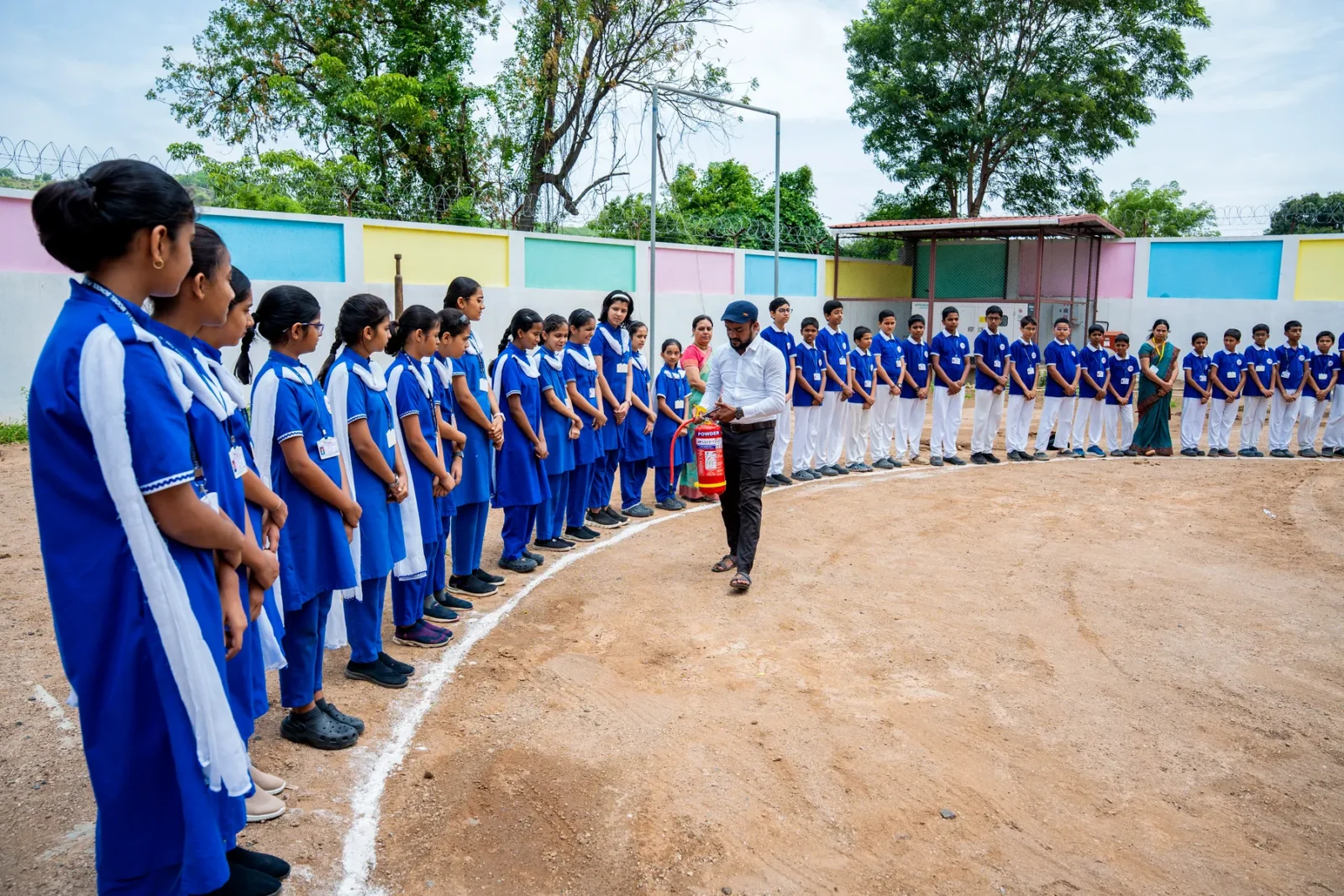 Senior students leading a whole-school circle formation on the ground