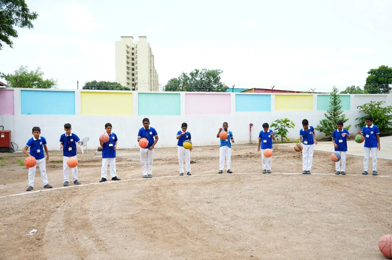 Students with practice balls on the ground in front of the boundary wall
